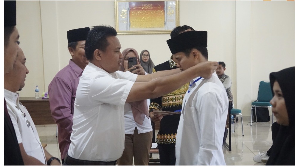 Foto Pimpinan Bawaslu mengalungkan tanda pengenal saat dilantiknya PTPS untuk PSU se-Kota Pariaman