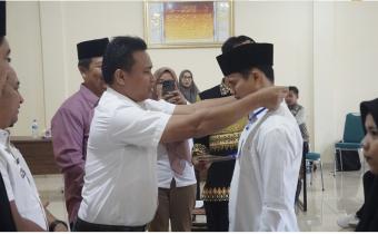 Foto Pimpinan Bawaslu mengalungkan tanda pengenal saat dilantiknya PTPS untuk PSU se-Kota Pariaman